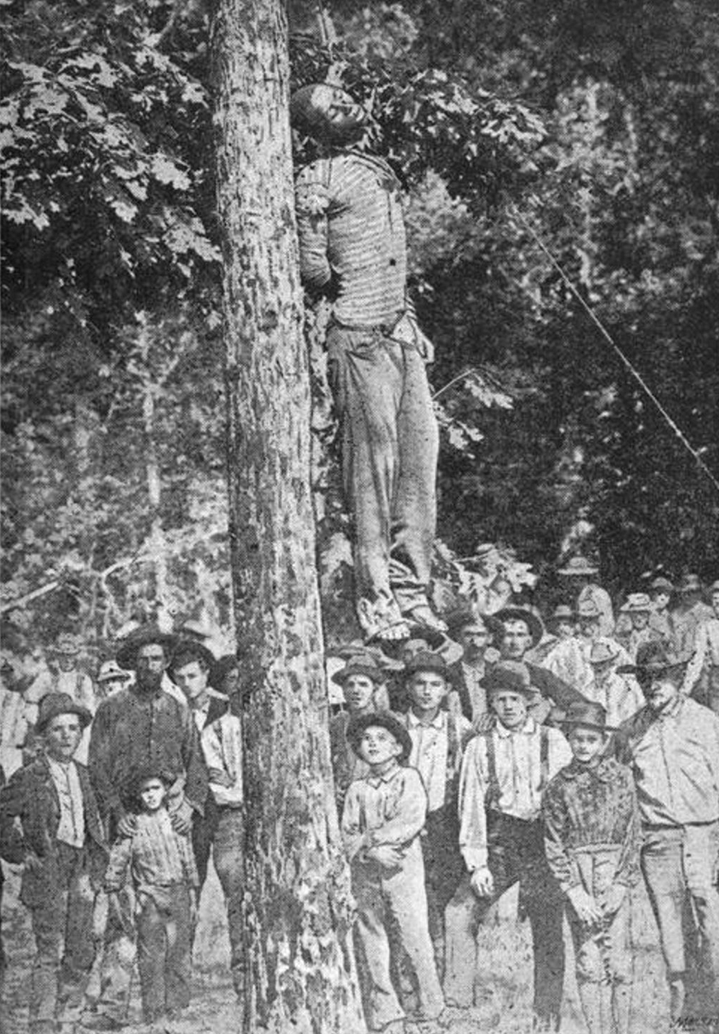 White children and parents gathered around a hanged Black man