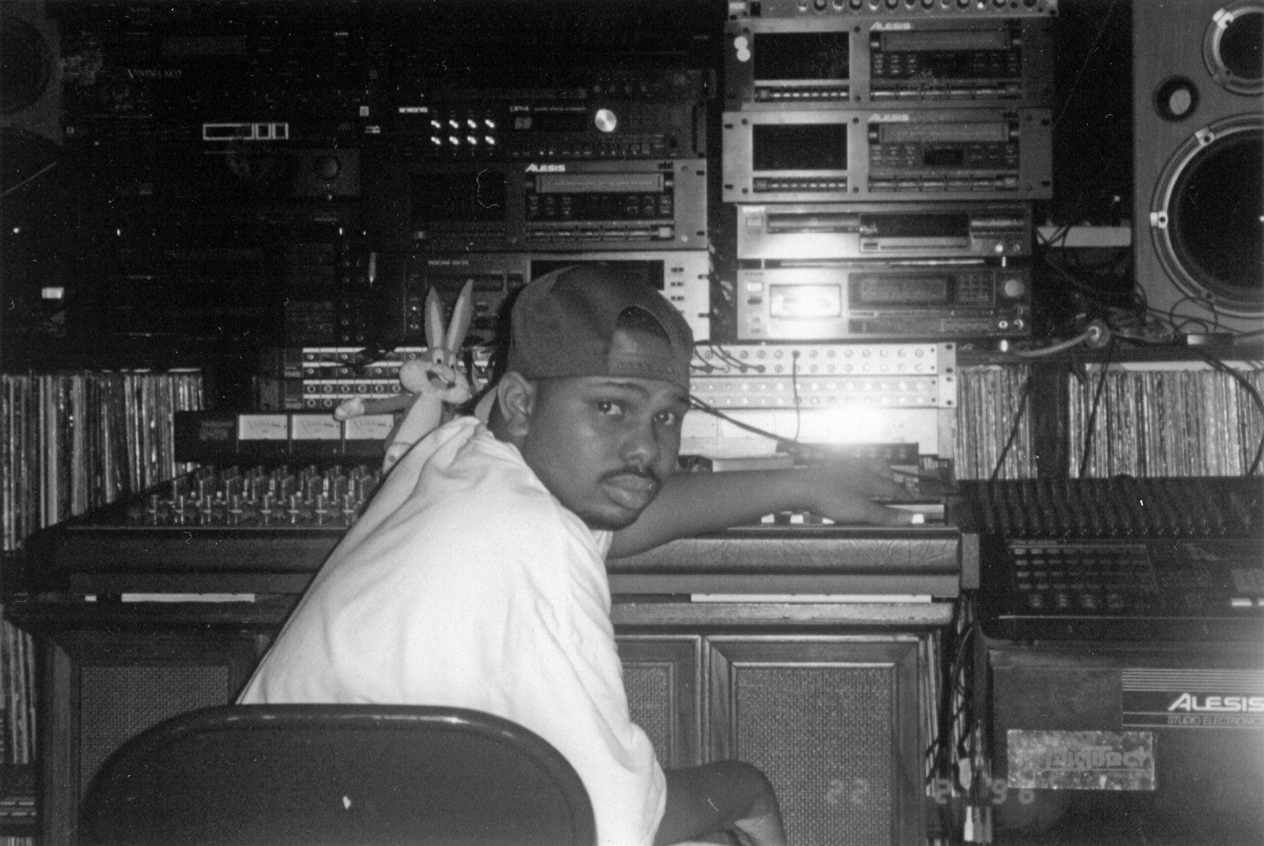 DJ Screw seated in studio, surrounded by recording equipment with a Bugs Bunny doll visible.