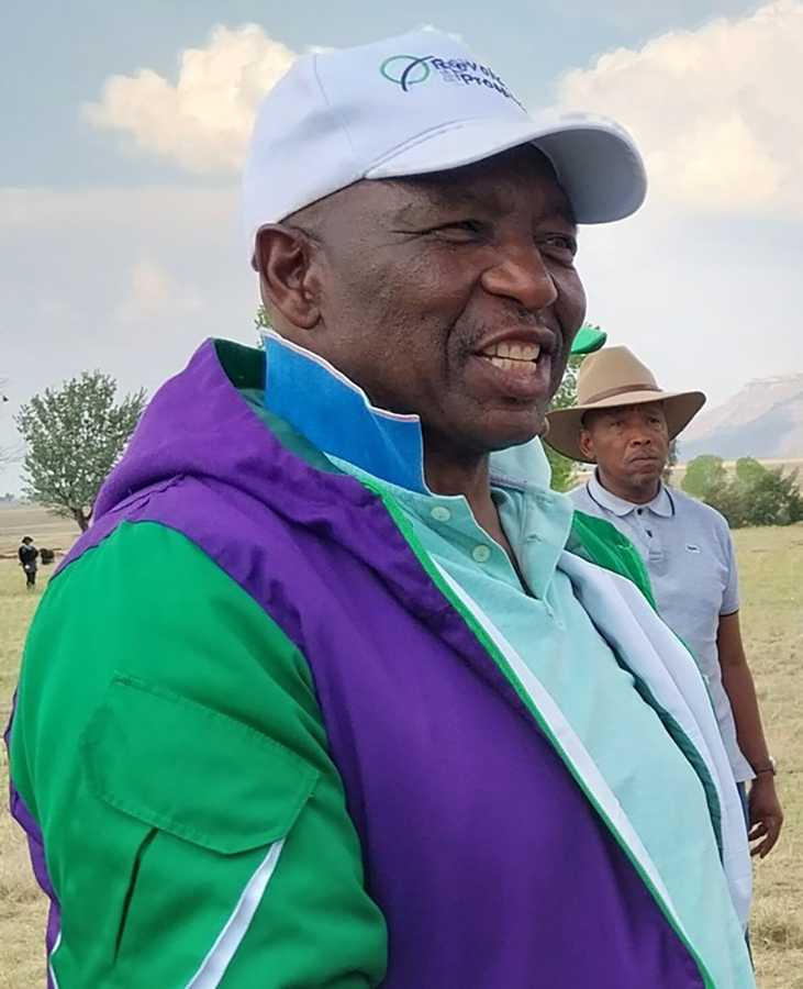 Matekane smiling in a purple and green jacket in the countryside