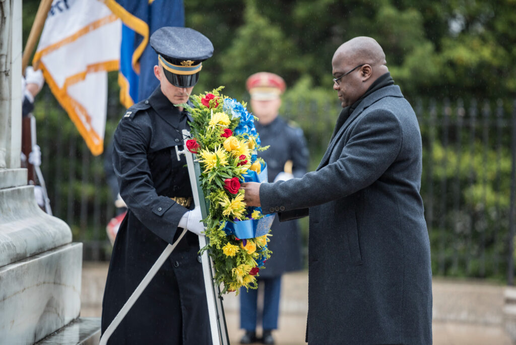 Tshisekedi touching a propped wreath in front of a soldier