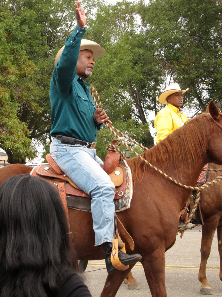 James Pickens Jr. waving while riding a horse