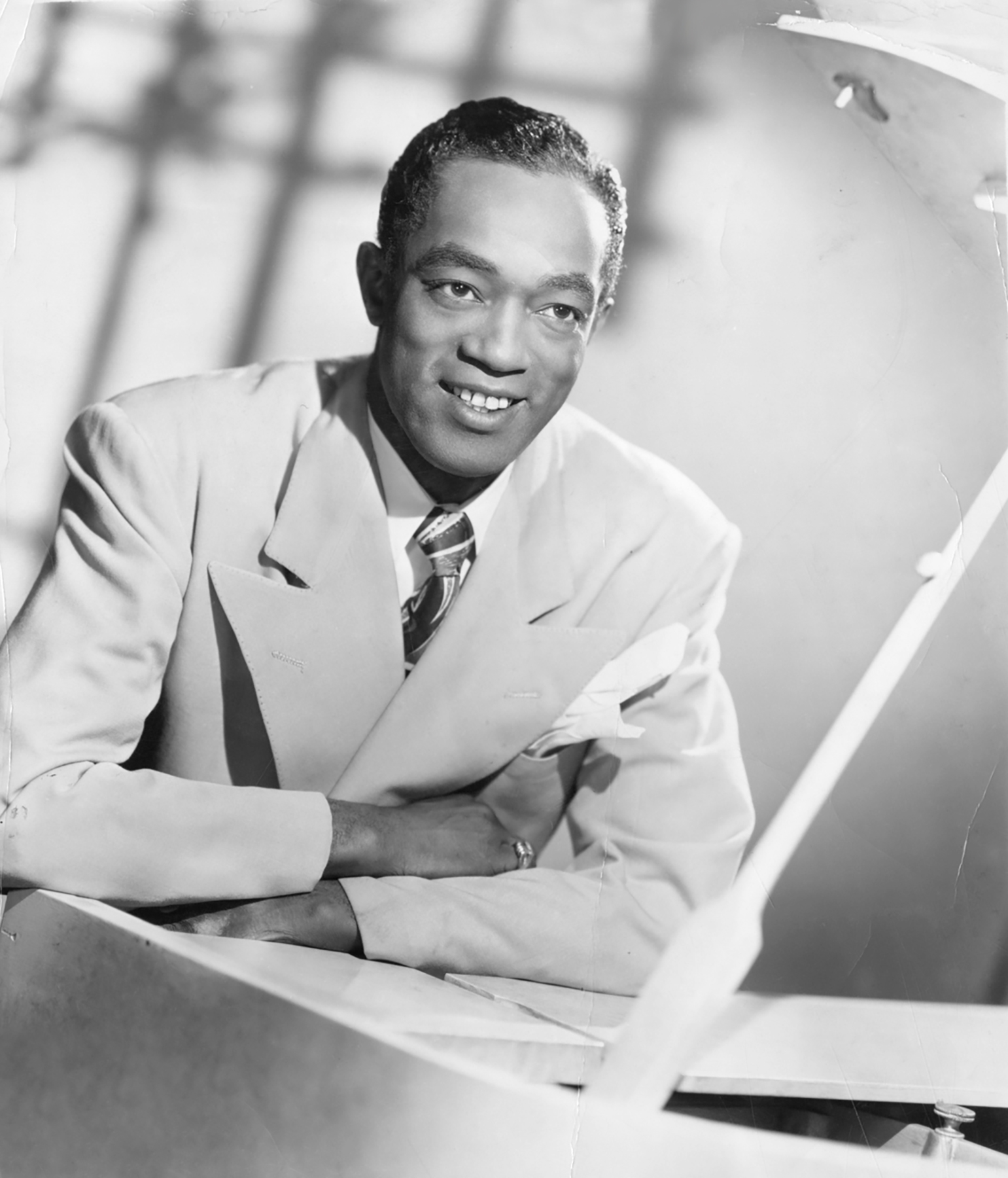 Buddy Johnson leaning on a piano smiling