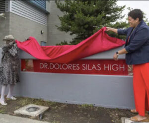 Silas revealing the new school name under a red cloth banner