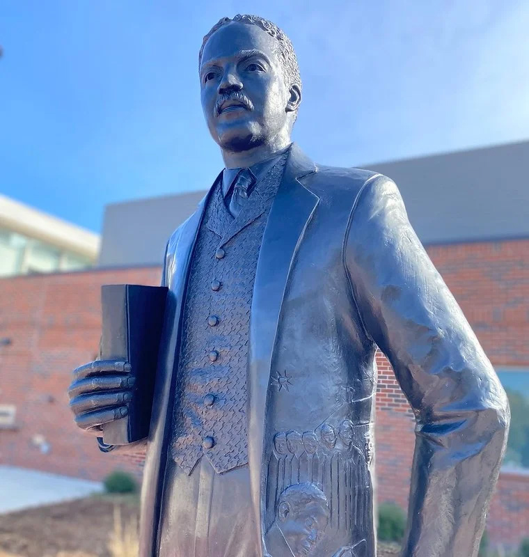 Statue of Richard Allen Tucker holding a Bible with a scene depicted on his jacket