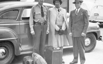Lucy Hicks stands with two deputy sheriffs in front of an automobile. Left to right: Deputy Sheriff (in uniform with hat) H.E. Bowman