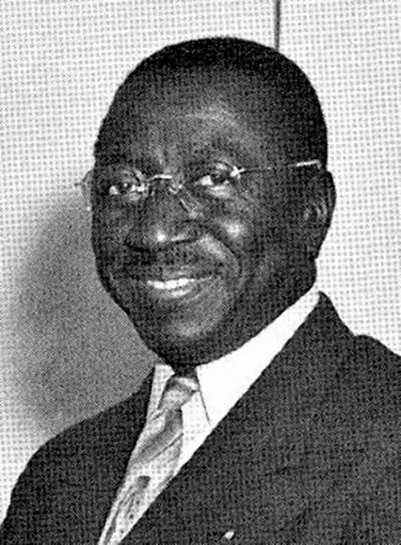 Black and white school employee portrait. Man wearing glasses with suit and tie.