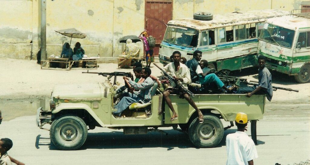 Armed group of men without uniforms riding in a tactical vehicle armed with automatic weapons