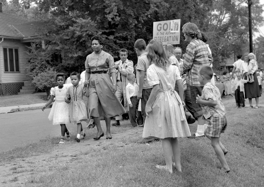 A photograph of Grace McKinley escorting her daughter Linda Gail McKinley (second girl) and a friend to Fehr Elementary School, corner of Fifth Avenue and Garfield Street, Nashville, Tennessee, 9 September 1957. Mrs. McKinley walks through an irate crowd of segregationists carrying picket signs and protestors of public school desegregation.